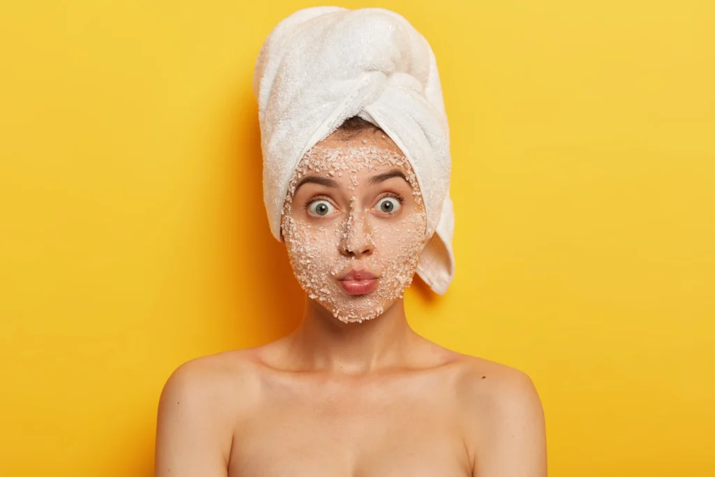 Zdjęcie kobiety wykonującej peeling do twarzy w ręczniku na głowie